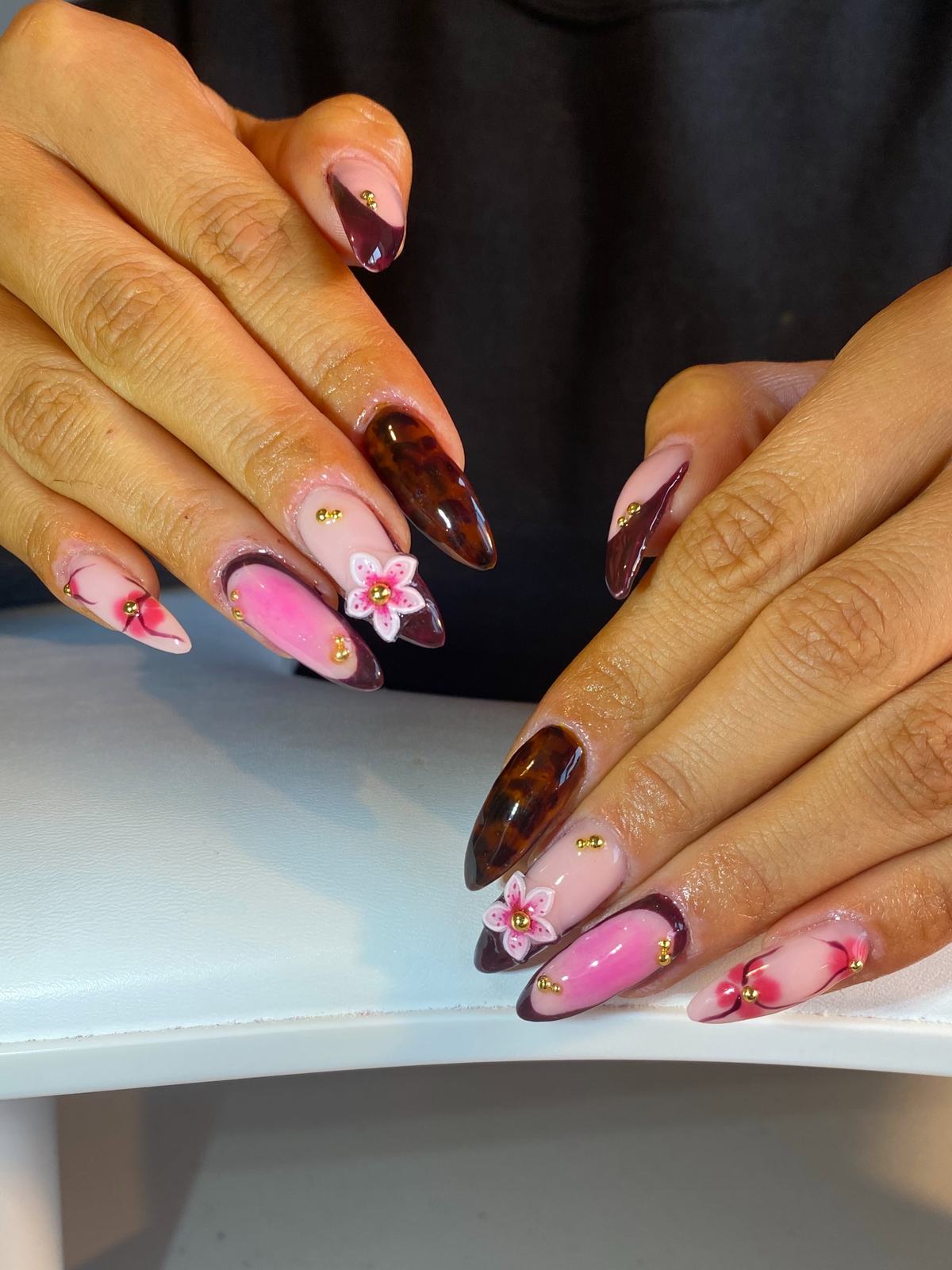 Stiletto nails in tortoiseshell and hot-pink aura with a 3D flower and gold beads