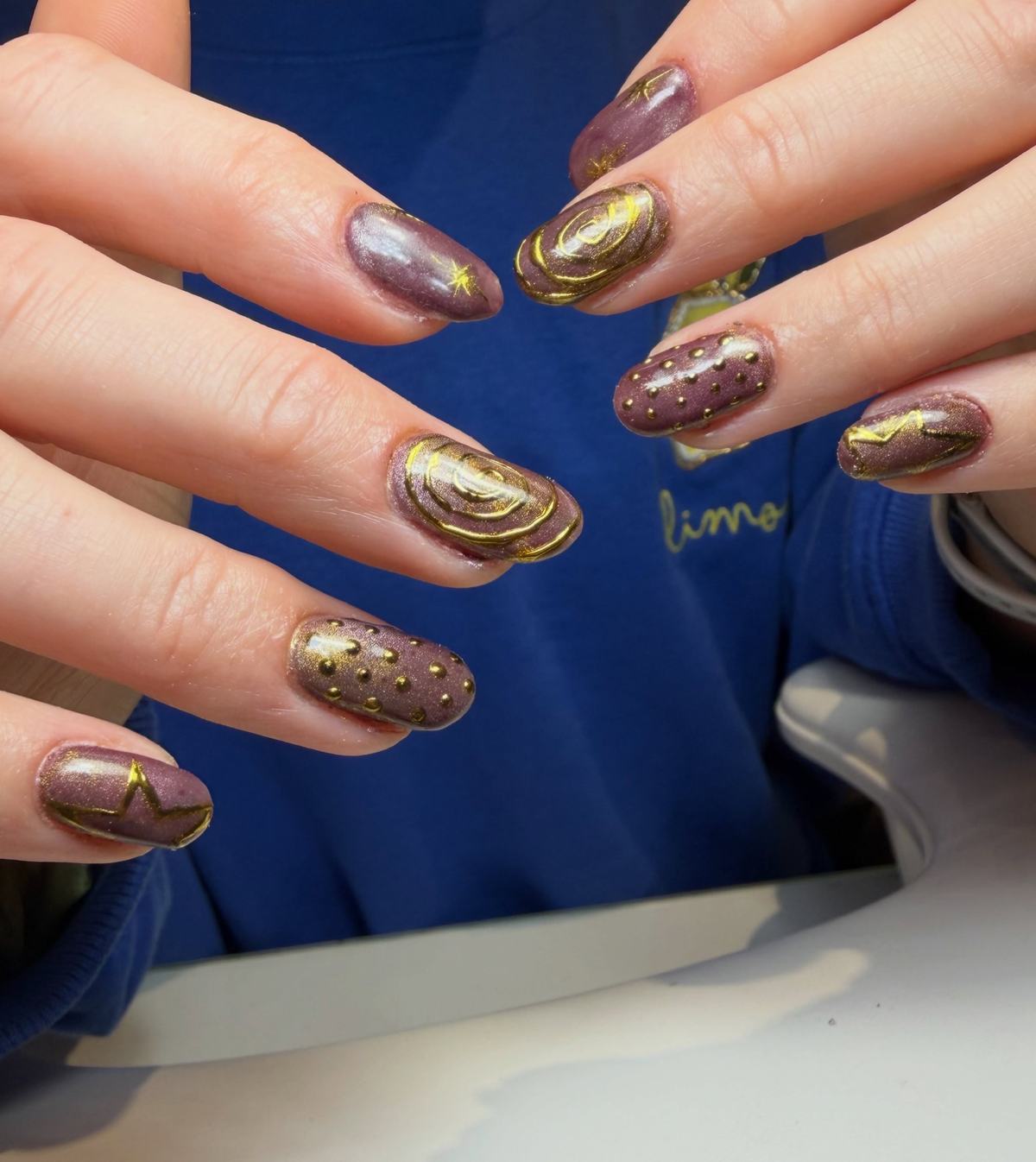 Mauve chrome nails with gold swirl and star line art and gold bead texture